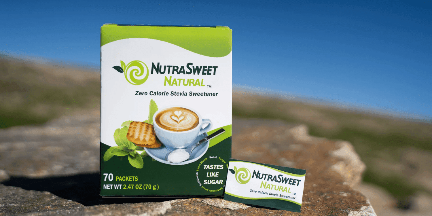 A box of NutraSweet sweetener packets outdoors on a rocky surface